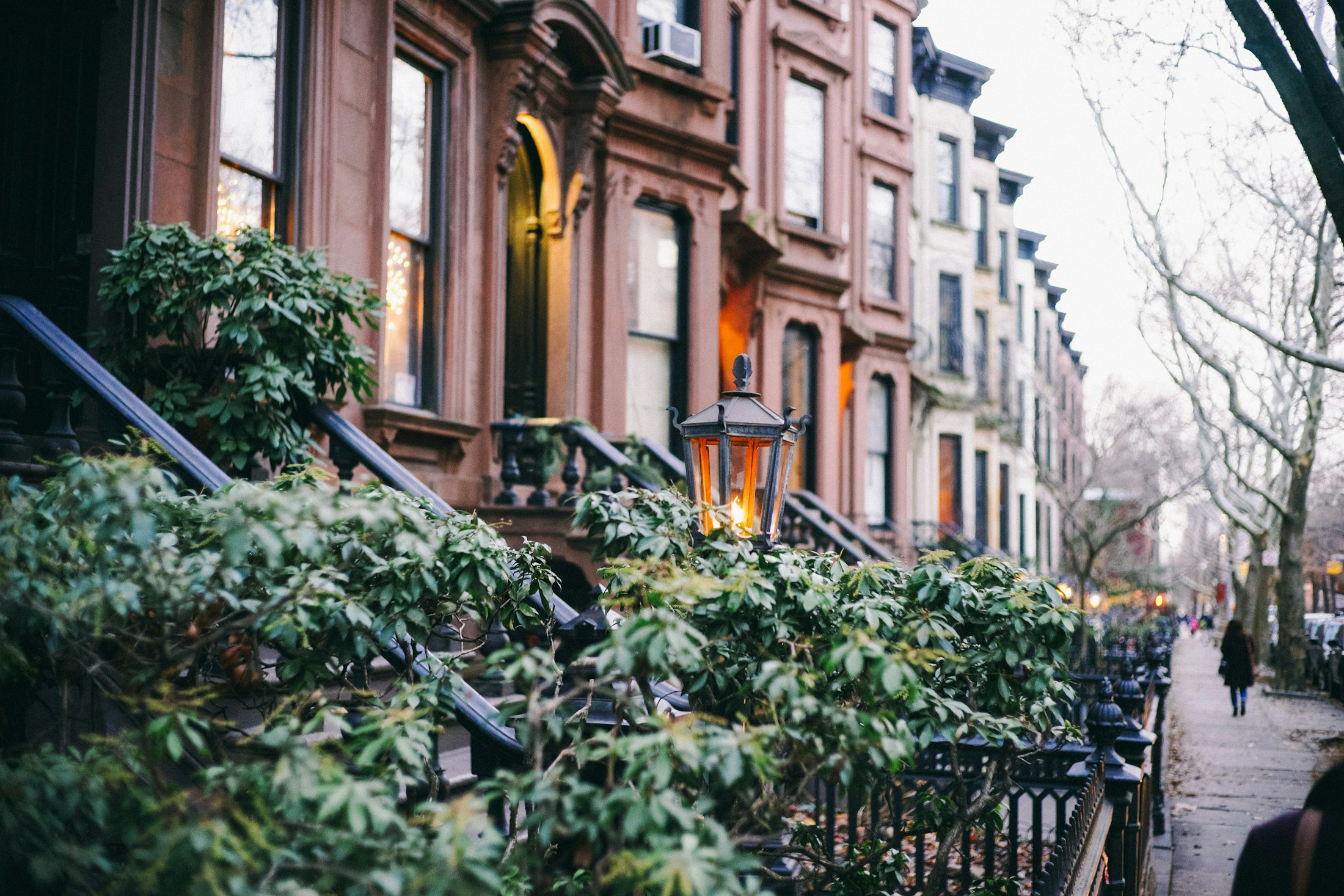 New York brownstone stoops, masonry facades, and iron railings along a tree-lined street